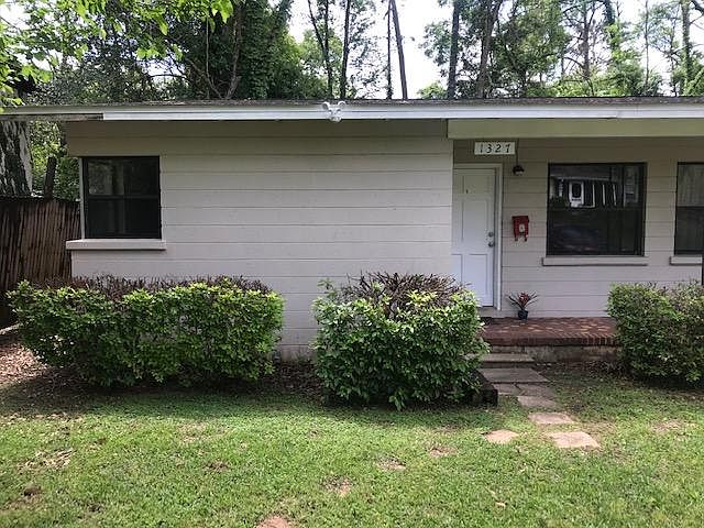 Front yard with recently trimmed hedges and motion-detecting flood lights.