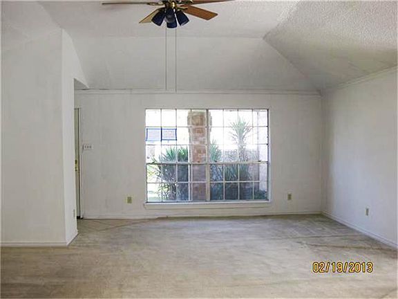 Living area is accented with high ceilings and a ceiling fan.