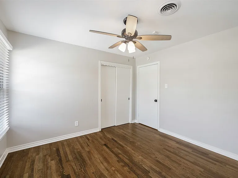 Unfurnished bedroom with multiple windows, dark wood-type flooring, a closet, and ceiling fan