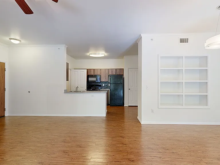 Apartment kitchen, dining and living room with wood-style flooring.