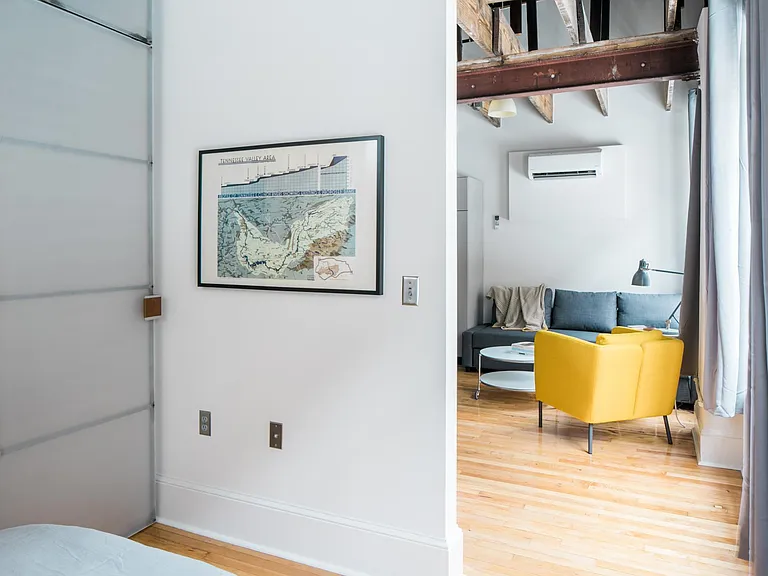 Bedroom includes designer furniture with under-bed storage, as well as custom designed feature closet door