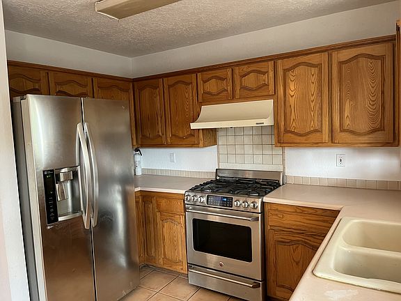 Kitchen with new stainless steel gas range and LG refrigerator.