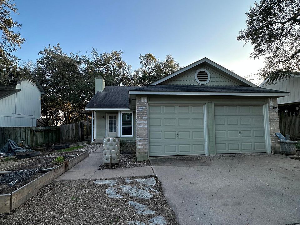 Two car garage and driveway. Garden beds.