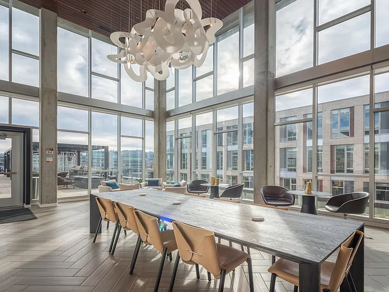 Interior resident lounge with floor to ceiling windows, large table, and artistic light features