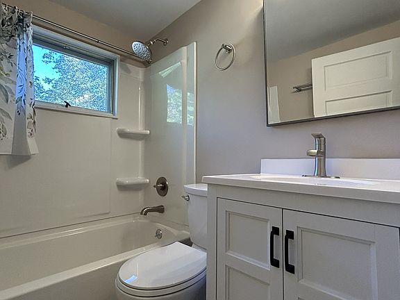 Bathroom completely remodel with brand new tile flooring, bath tub, vanity, mirror, light fixture and toilet.