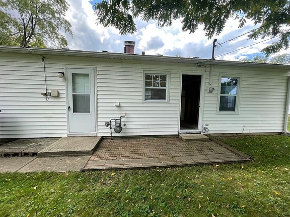 Small Brick Patio in Back. Closed Door to Kitchen. Open Door to Back Storage Closet.