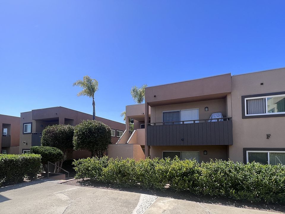 Private patios and balconies amongst manicured bushes and trees at Villa Pacific Apartments in Oceanside, California.