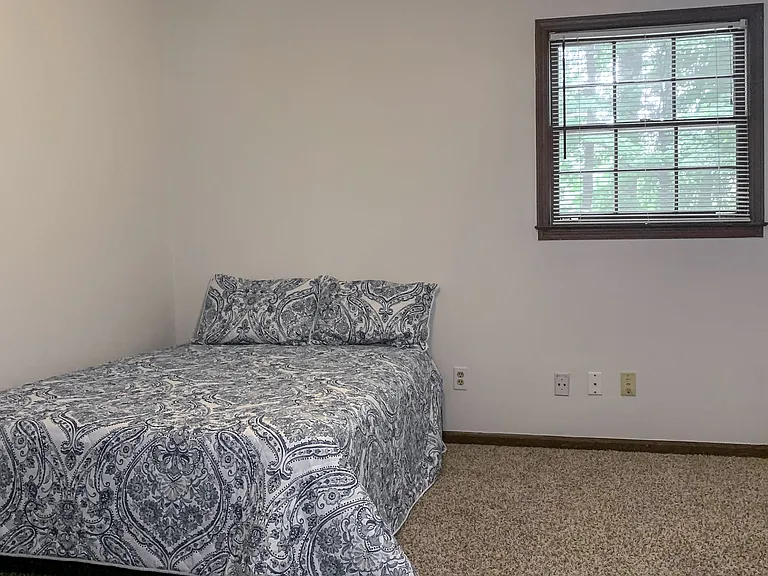 Upper level room featuring a full size bed, ceiling fan, & reach in closet.