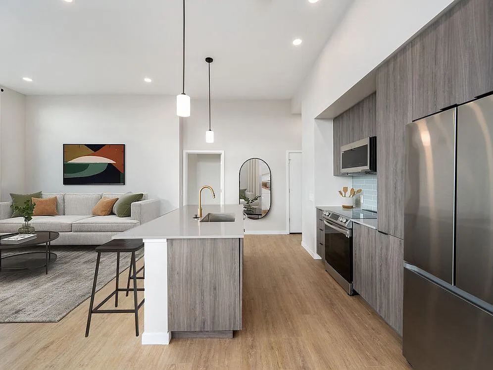 Signature Collection kitchen with dark cabinetry, marbled quartz countertops and backsplash, upgraded stainless steel appliances, and pendant lighting. - Avalon Governors Park