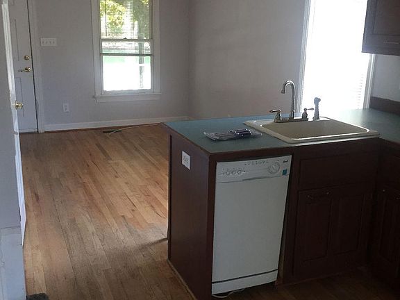 Kitchen and living area from rear entrance. Stairway to upper level is on the immediate left, and half-bath on the left wall.
