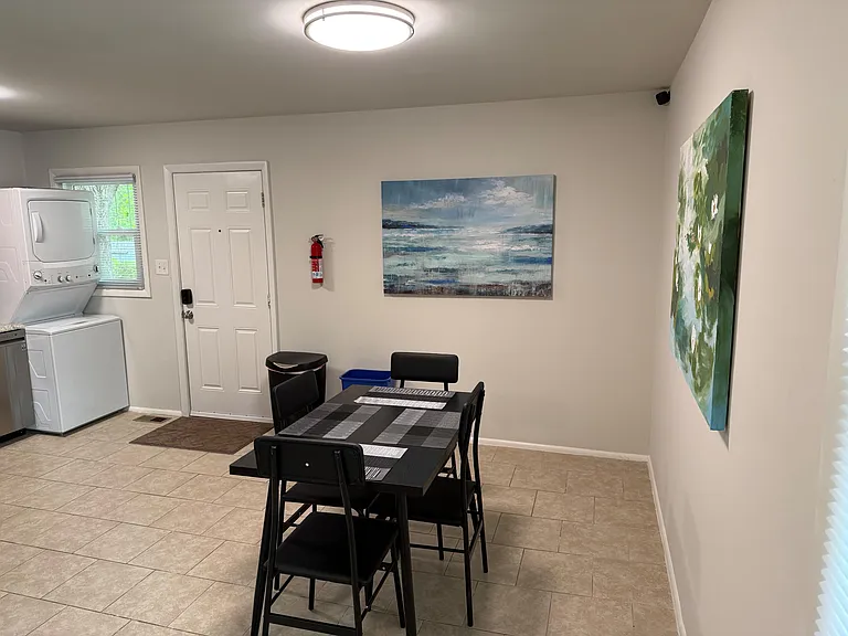 Dedicated dining area with a table for four, tile flooring, and convenient access to in-home laundry and entry.