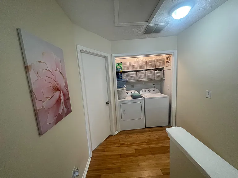 Convenient laundry nook with side-by-side washer/dryer and wire shelving for supplies and linens.