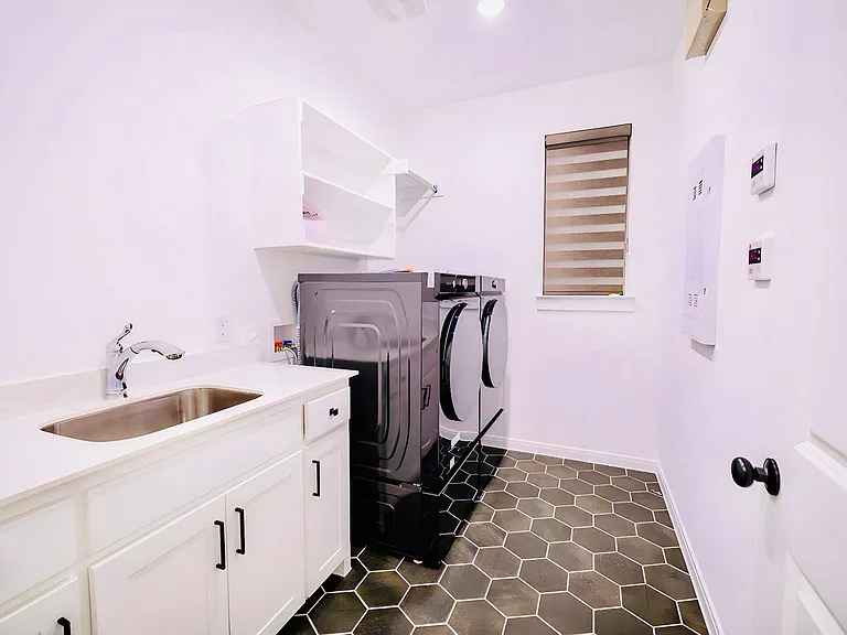 Washroom with dark tile patterned floors, separate washer and dryer, cabinet space, and electric panel
