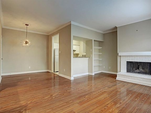 This perspective of the living area shows the wood burning fireplace with brick hearth, built-in bookcases and crown moulding throughout the area.  A neutral paint scheme will complement any decor.