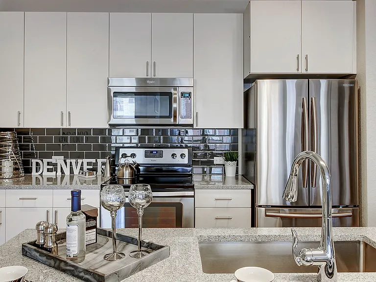 Apartment kitchen with stainless steel appliances, granite countertops and wood-style flooring.