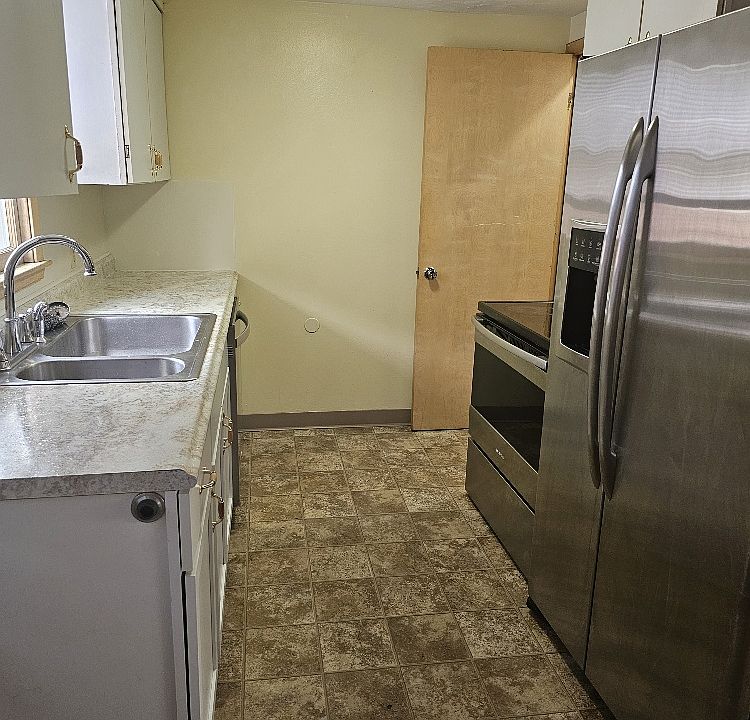 View of kitchen with stainless steel fridge and oven.