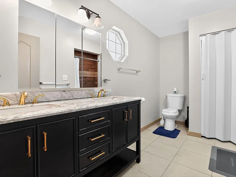 Full bathroom with double-sink marble-top vanity, large mirror, and a shower/tub combo with sliding doors.