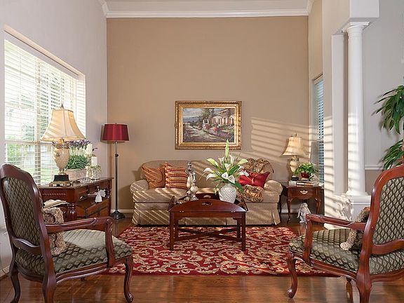 The living room has hardwood floors, crown moulding and decorative columns.
