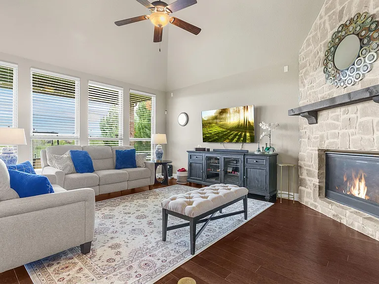 The corner, stone-encased gas log fireplace offers an engaging sense of hospitality in the family room. So much natural light from the vaulted celing & picture windows with greenbelt views. Ample room for many furniture placement options. Note the surroun