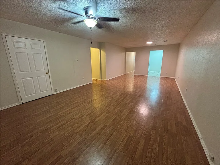 Spacious interior with wood-finish flooring, light-toned walls, and multiple doorways