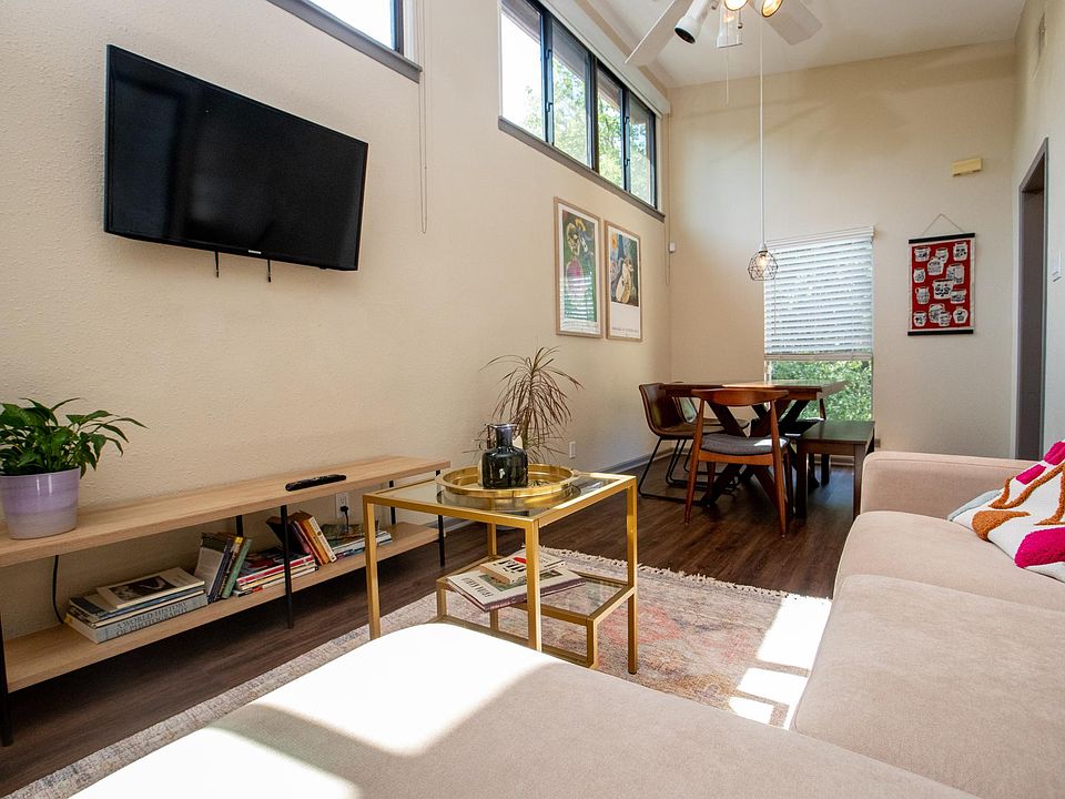 Living and dining area with high ceiling and large windows.