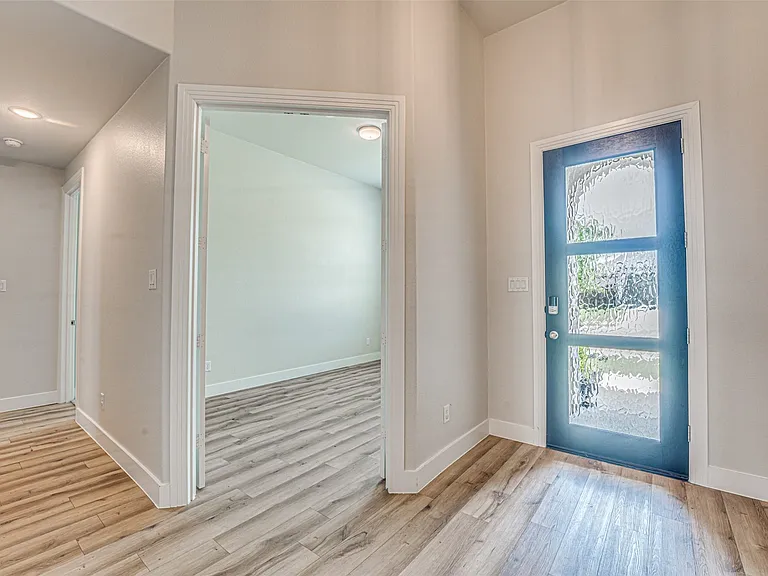 Entryway featuring a modern door with three textured glass panels, light wood-finish flooring, recessed lighting, and crisp white trim