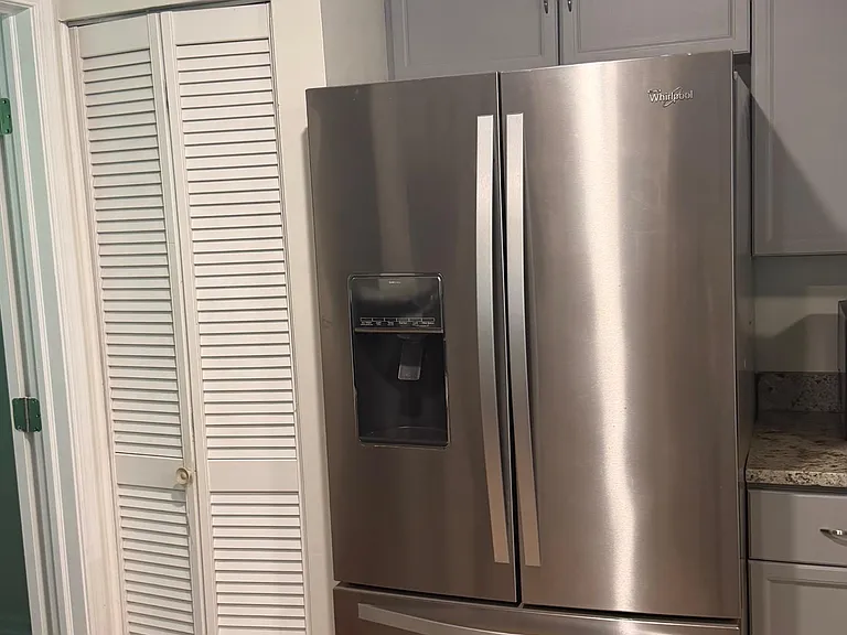 Kitchen with stainless French-door refrigerator, gray cabinetry, and adjacent pantry storage for everyday convenience.