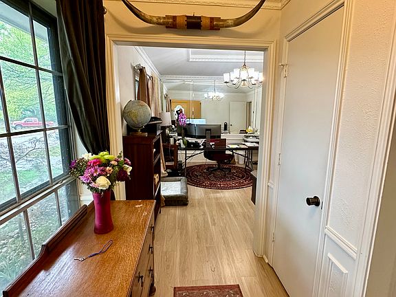 Entry hallway with ornamental molding, light wood finished floors and a chandelier