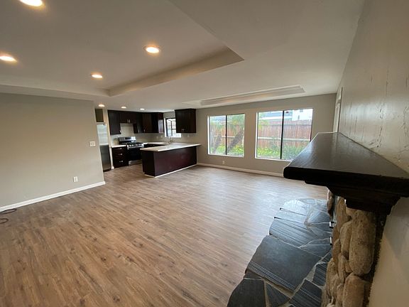 Great room with living room, dining room, and kitchen. Mantle and hearth of wood burning fireplace