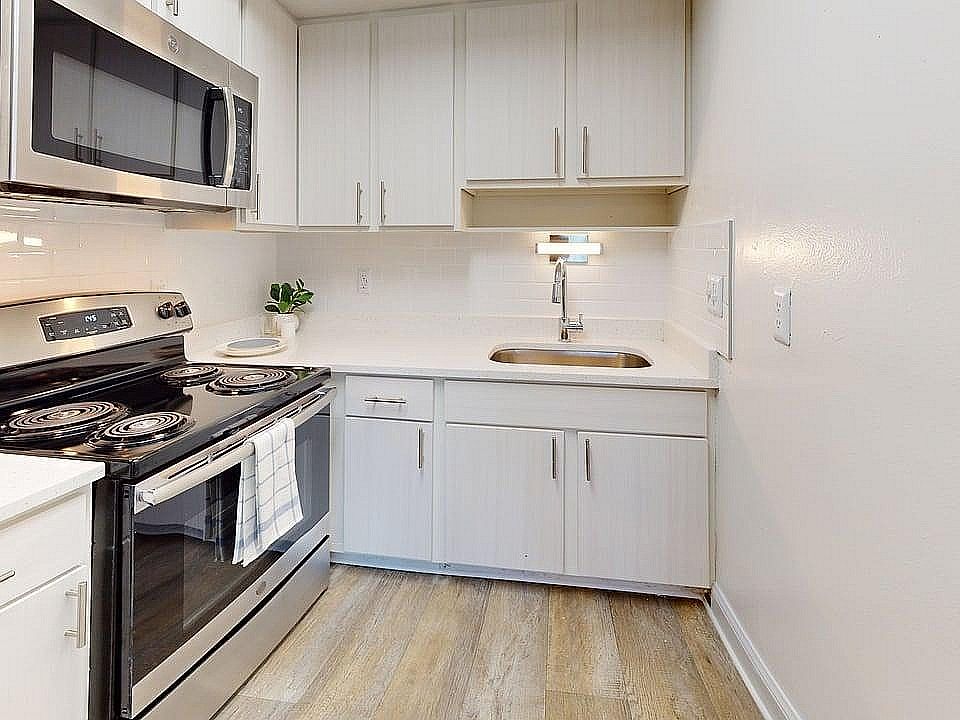 Modern kitchen with stylish stainless steel appliances, sleek white cabinetry, and elegant wood flooring, ideal for culinary enthusiasts.