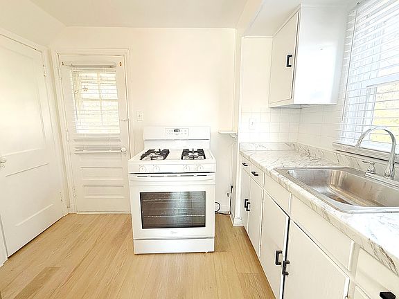 First floor _ newly renovated kitchen with brand-new French-door refrigerator, 4-burner stove, microwave and modern countertops, offering a clean and functional cooking space.