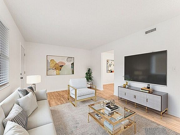 Chic modern living room with natural light, stylish furnishings, and a sleek flat-screen TV.