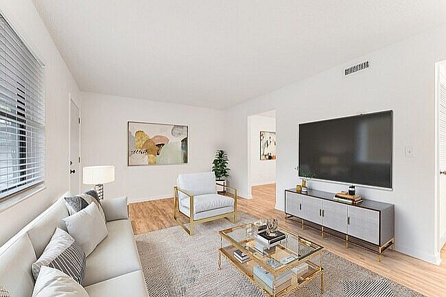 Chic modern living room with natural light, stylish furnishings, and a sleek flat-screen TV.