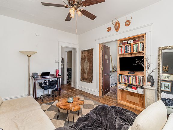 living room leading to one of bedrooms by open door. built in bookshelf next to door.