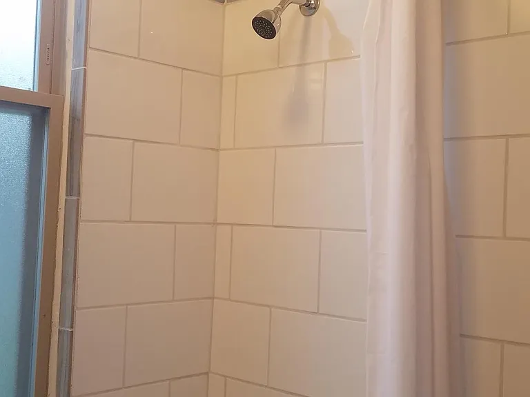 Detail of new subway tile tub surround with glass tile accents.