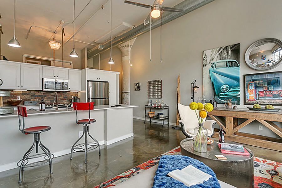 Living room with open concept kitchen, concrete floor, and beautiful white cabinets. Loft style apartment