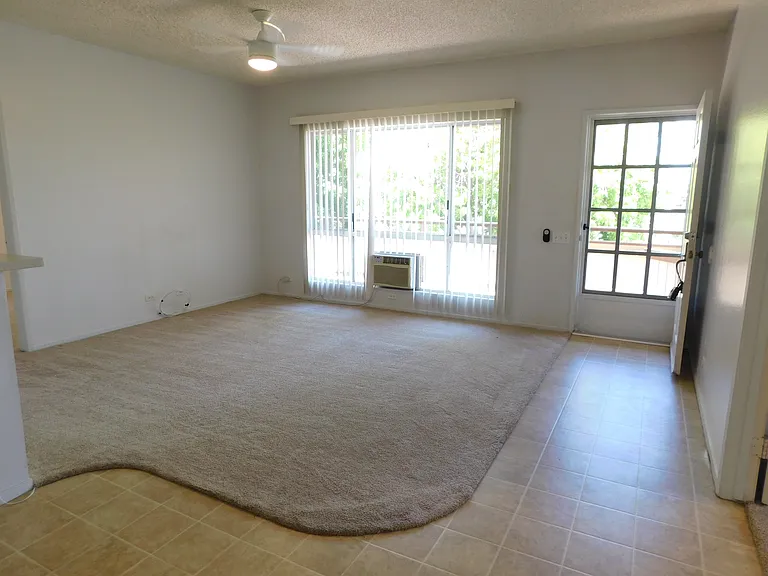 View of living area. Newer carpet/padding. Ceiling fan and window a/c. Full-length lanai in the front of the unit.