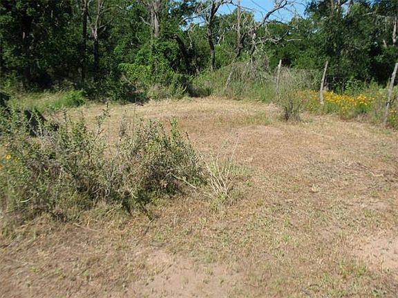 Partially mowed area inside fence around abandoned house