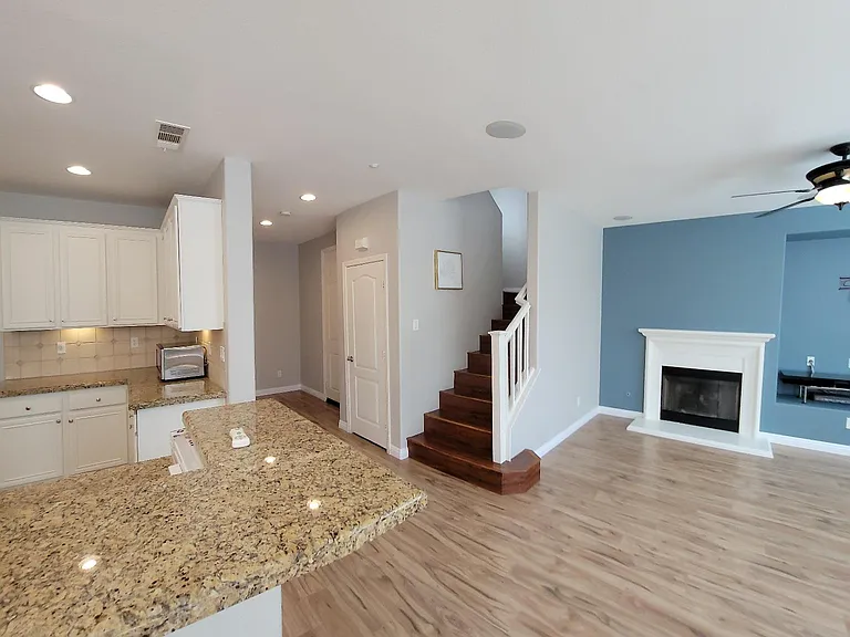 View of kitchen, entry hallway, stairs and fireplace (from left to right)