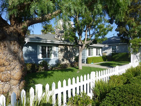 Front of home with fenced in yard and trees