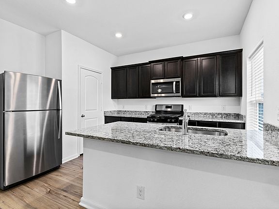 Designer kitchen with granite countertops, stainless steel appliances, and wood-style flooring.