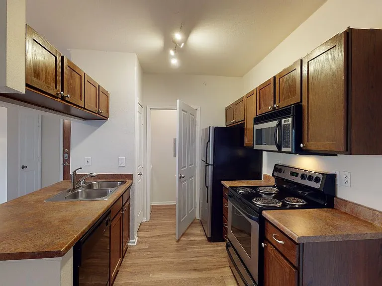 Apartment kitchen with wood-style flooring.