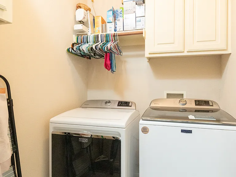 Convenient laundry room with a washer, dryer, storage cabinets, and hangers. Easy and efficient for longer stays or freshening up clothes during your trip.