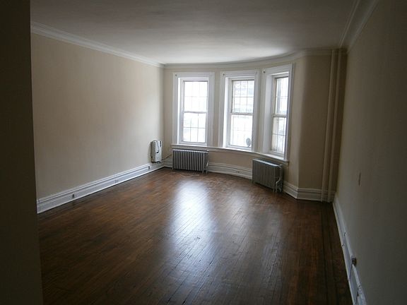 Front bedroom with hardwood floor and large windows over fro
