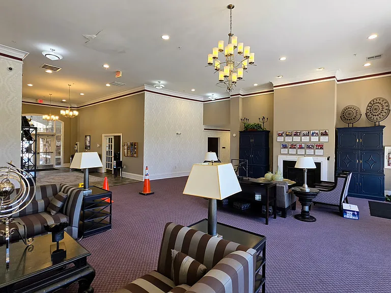 Spacious clubhouse lobby boasting towering ceilings, refined light fixtures, and a warm, welcoming fireplace hearth.