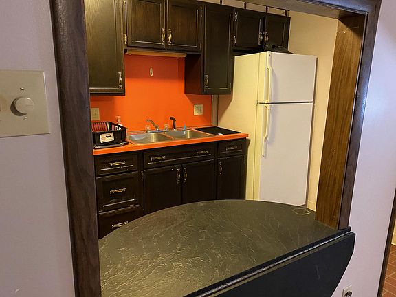 view of kitchen from living room side with half table.