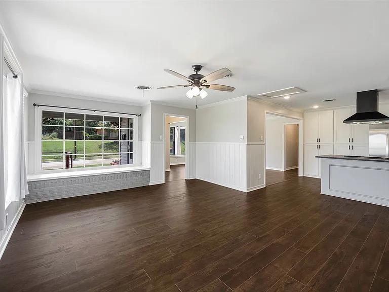 Unfurnished family room featuring crown molding, dark wood-type flooring, and ceiling fan