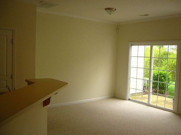 Spacious dining area next to kitchen overlooking patio and wooded area.