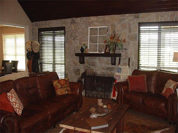 The living room has a stone accent wall, woodburning fireplace w/gas connections & ceramic tile floo
