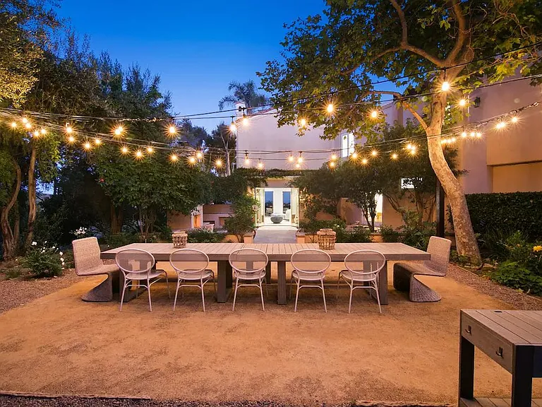 Outdoor dining space that seats 12 with warming string lights.